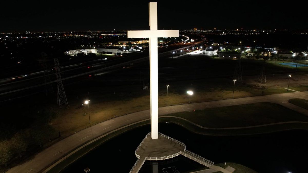 Night aerial drone photo of an illuminated cross and highway lights
