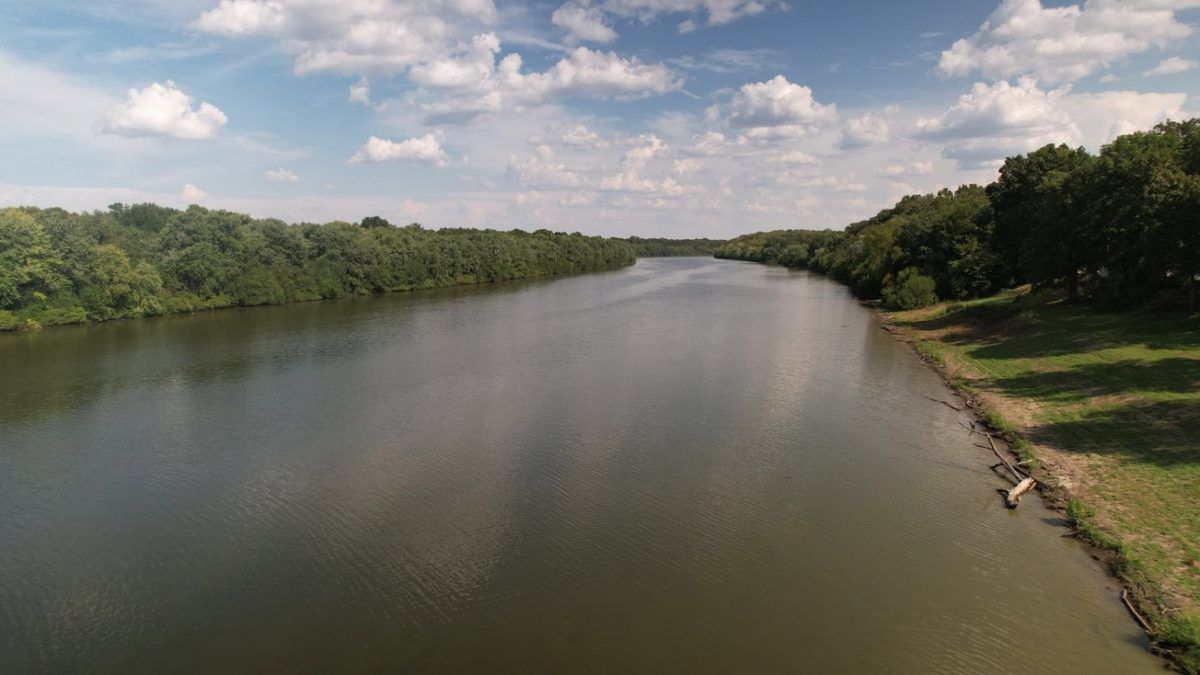 Drone photo of a calm river reflecting clouds