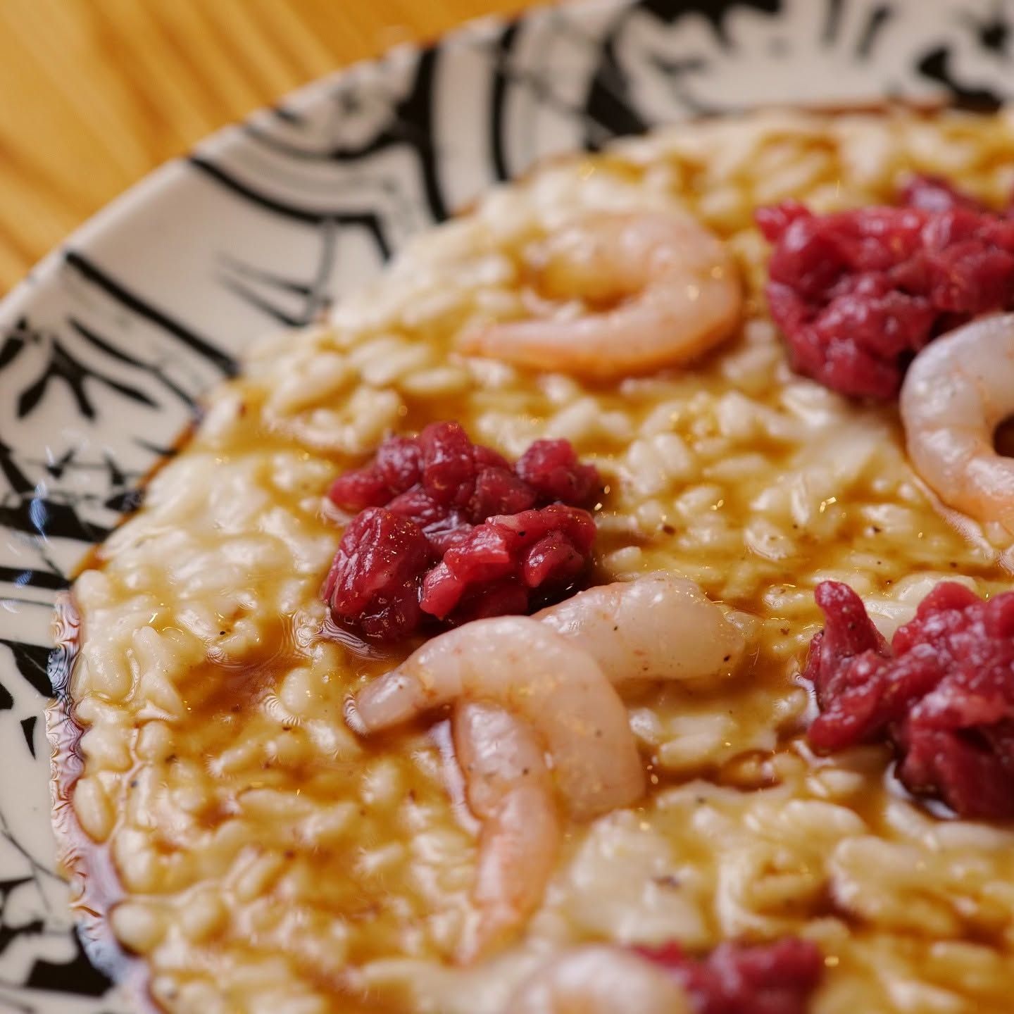 Risotto con gamberi e salsa rossa su un piatto decorato, primo piano.