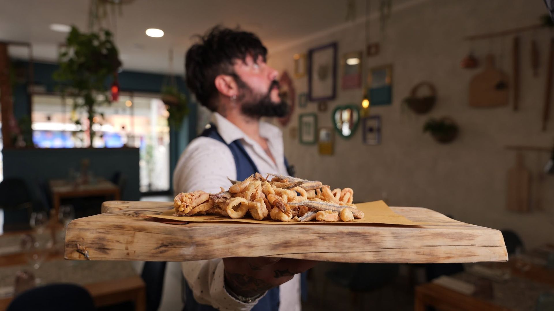 Un uomo che trasporta un vassoio di cibo nella cucina accogliente di un ristorante, guardando in alto.