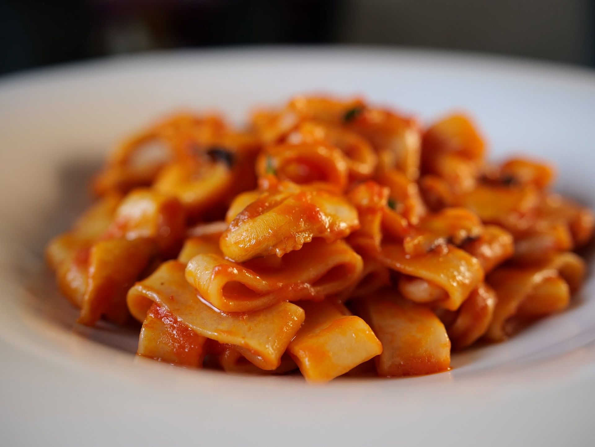 Piatto di pasta al sugo di pomodoro su un piatto bianco.