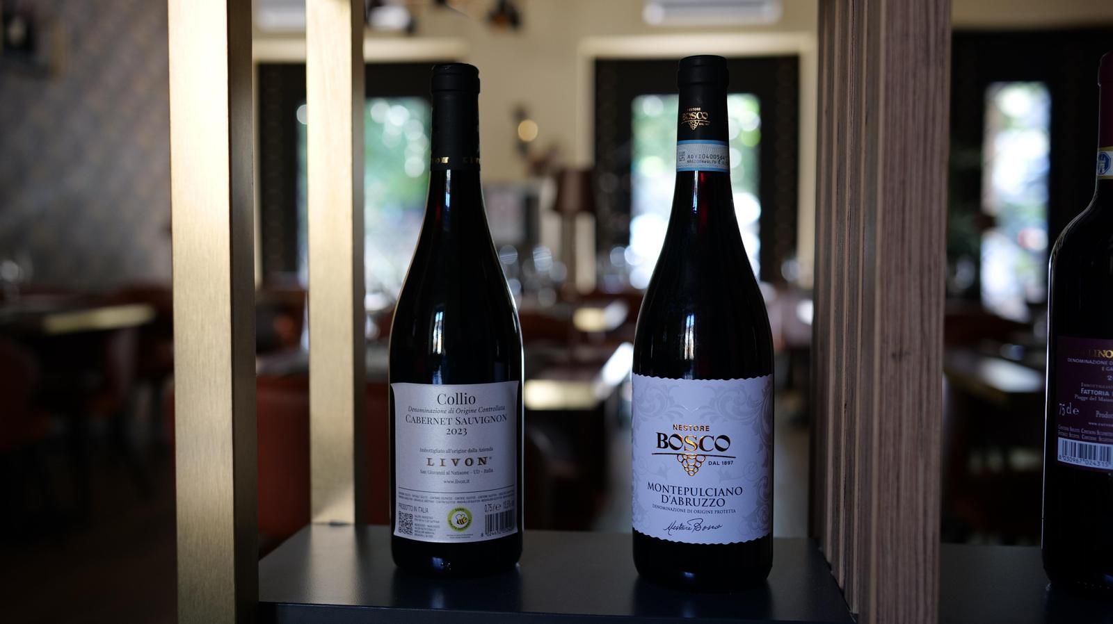Mano che regge un piatto gourmet impreziosito da un'elegante ghirlanda, incorniciato in oro e sormontato da tralci di vite verdi.