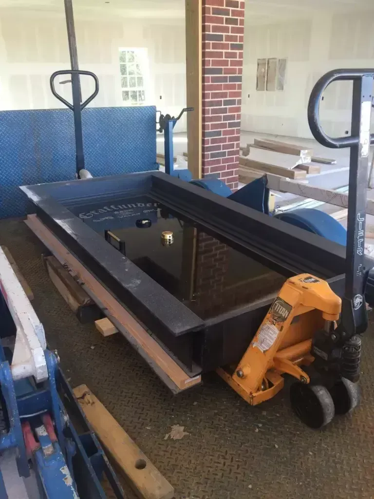 Black stairlift or platform lift in a workshop, with an orange motorized base and blue padding nearby