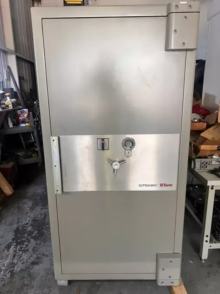 Tall gray metal safe or cabinet with a silver lock panel in a storage area.