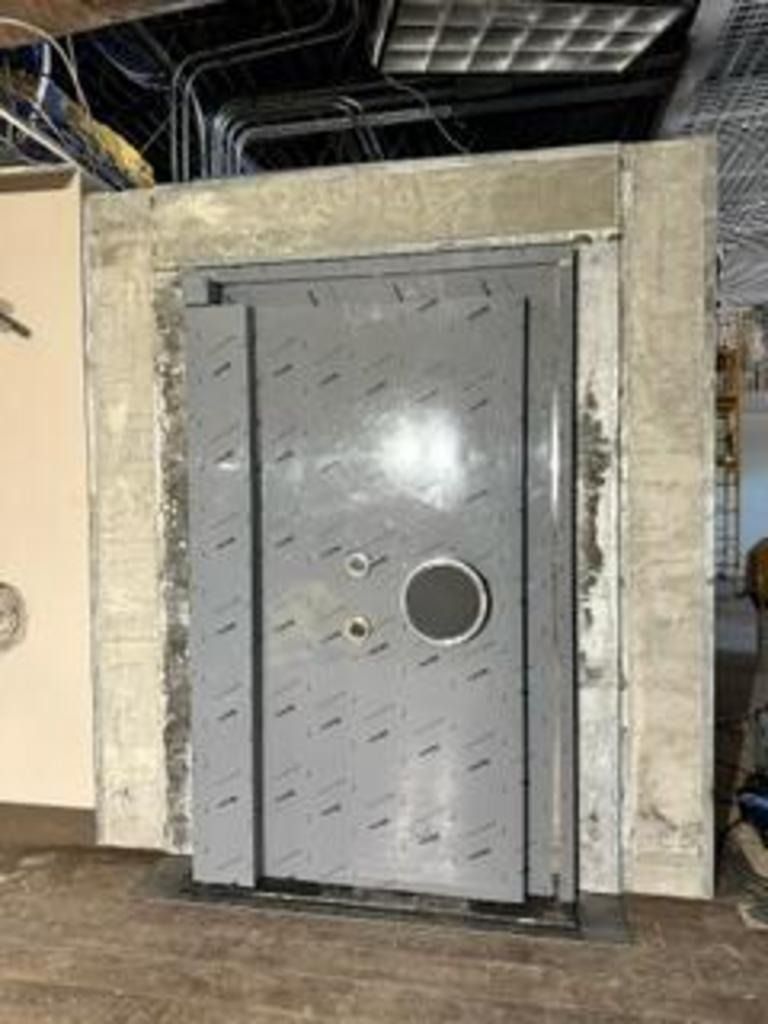 Gray industrial metal door with a round porthole in a warehouse-like wall opening