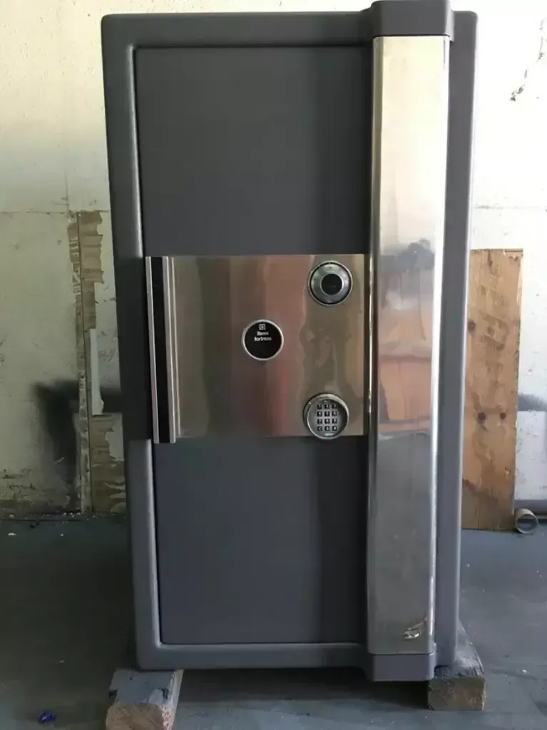 Gray wall-mounted metal safe with a shiny steel panel and three circular locks.