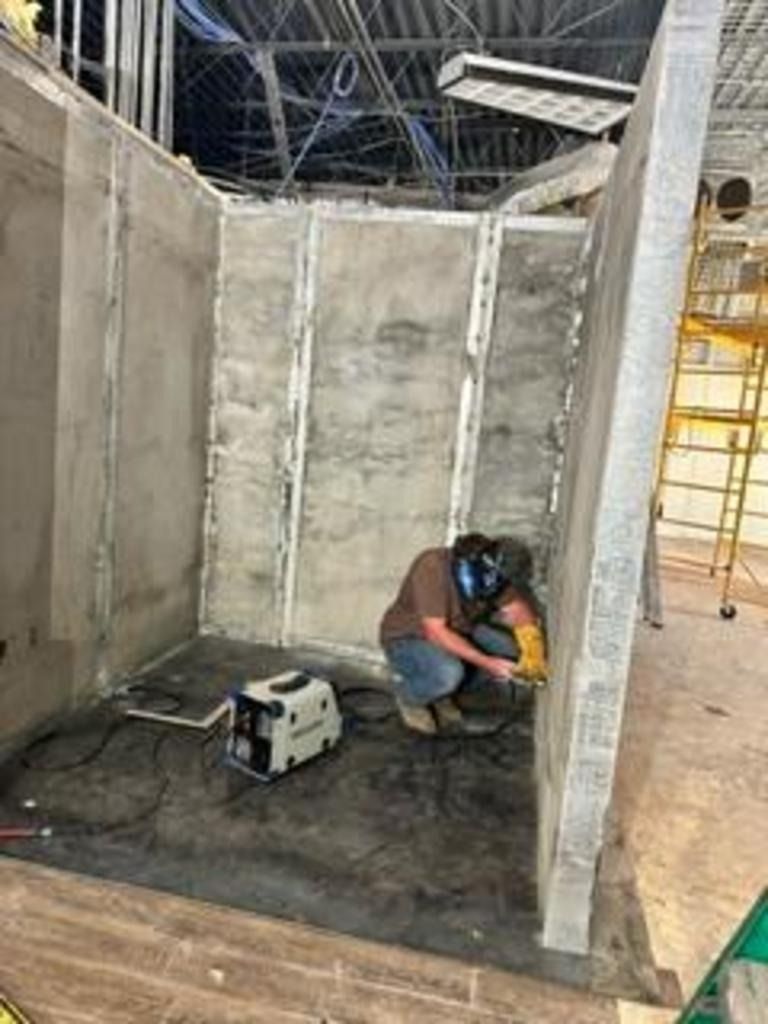 Worker using a power tool inside a concrete room under construction