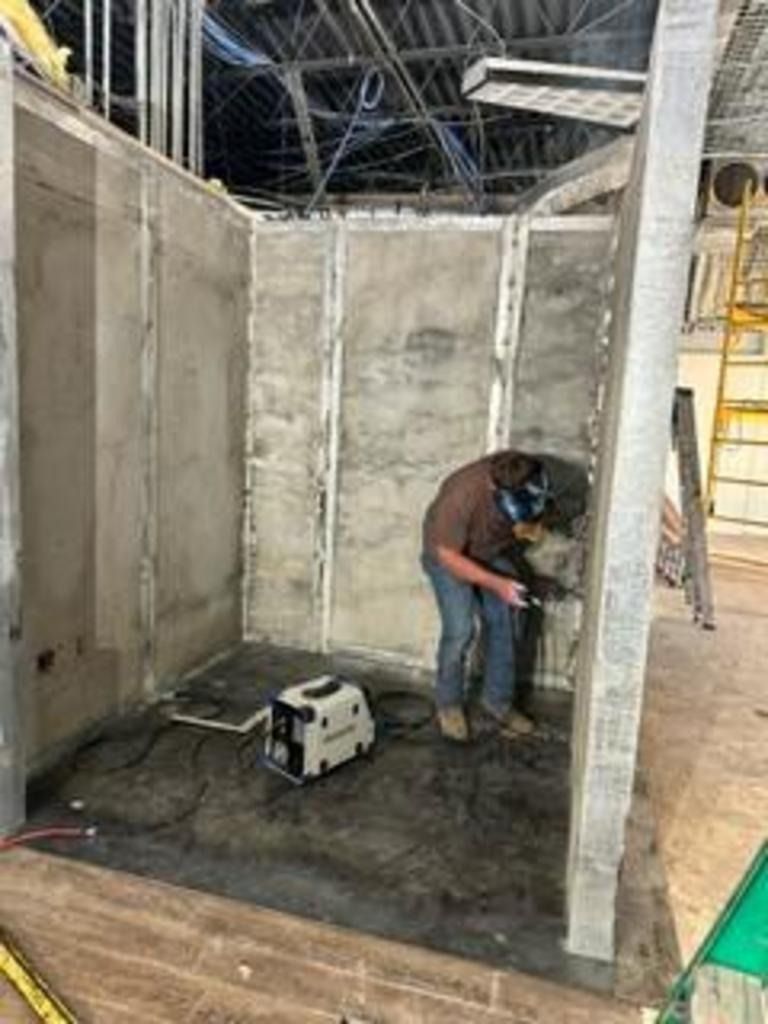 Worker using a power tool inside a partially built concrete room under construction