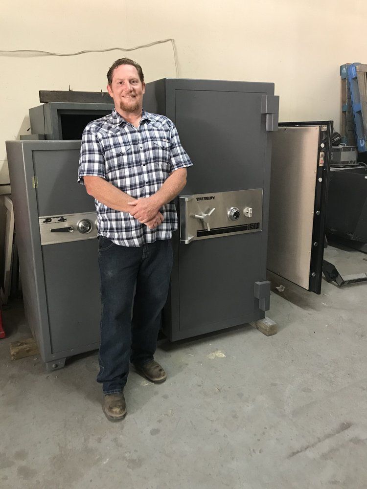 Man standing in front of a large industrial machine in a workshop, wearing a plaid shirt and jeans.