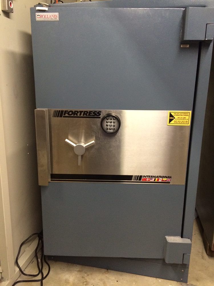 Gray Fortress safe with a silver door and combination lock in a corner.