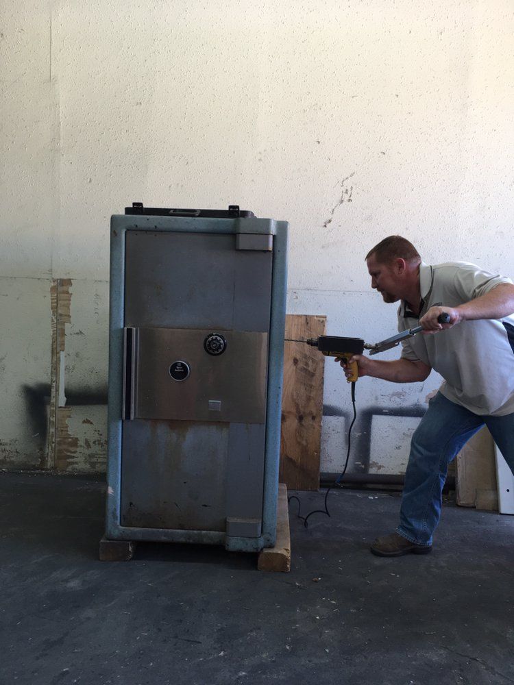 Worker using a power tool beside a large metal cabinet in an industrial setting