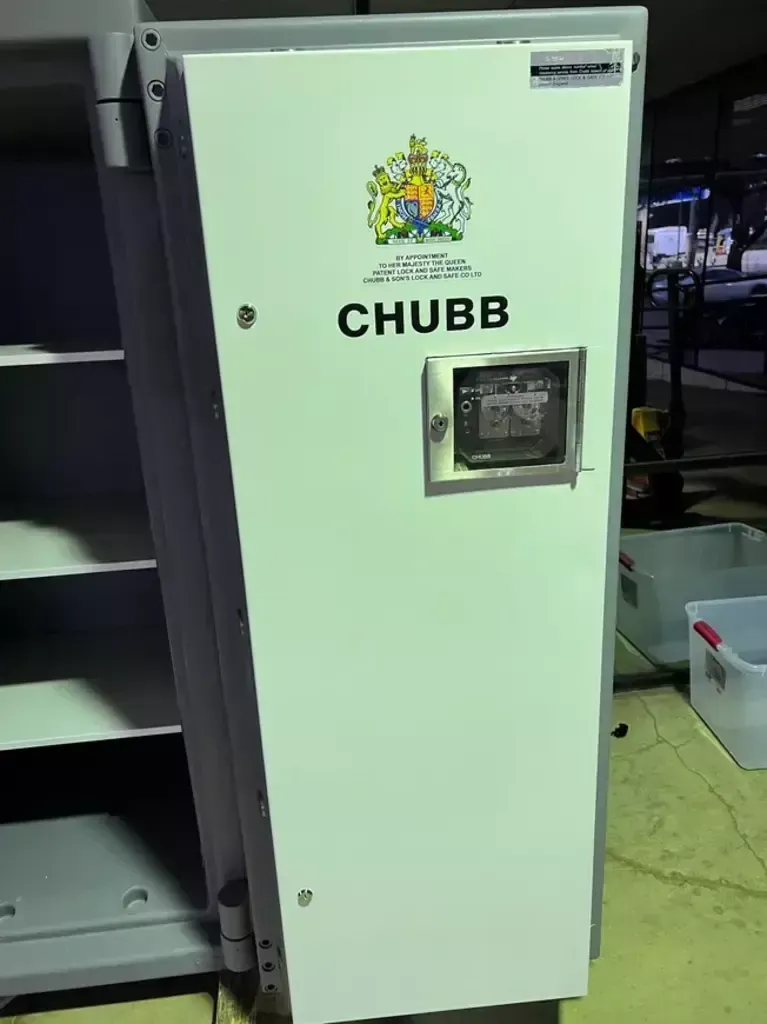 White CHUBB security cabinet with a small display, standing in an industrial setting.