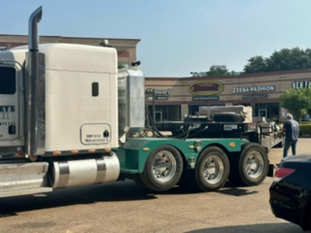 Teal semi-truck with chrome tanks parked at an outdoor truck show