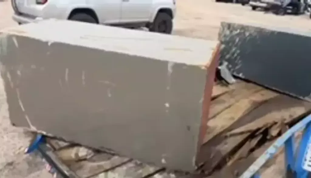 Large gray rectangular cabinet or appliance sitting on a flatbed trailer outdoors
