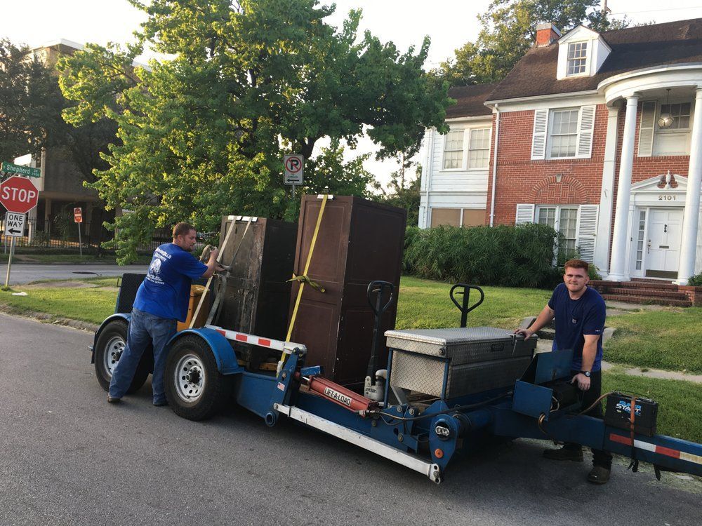 Two workers hauling furniture on a trailer in a residential neighborhood