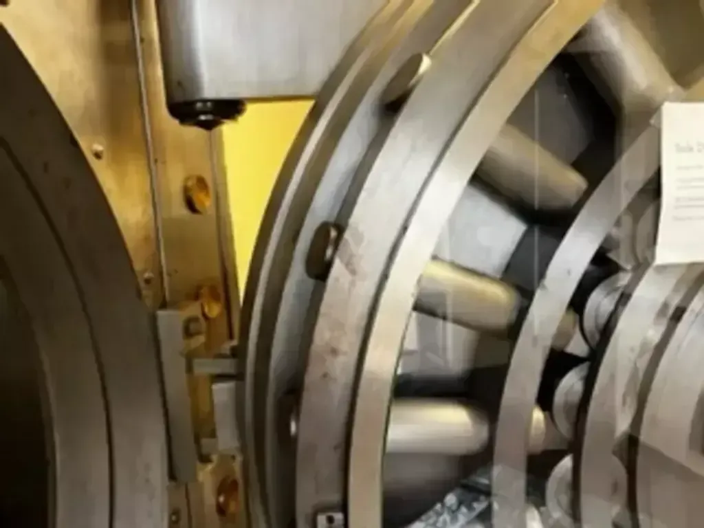 Close-up of a metal bank vault door with heavy locking bolts and a yellow inner panel.
