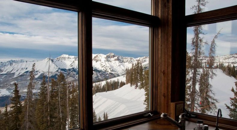 Snowy mountain landscape viewed through a wooden-framed window
