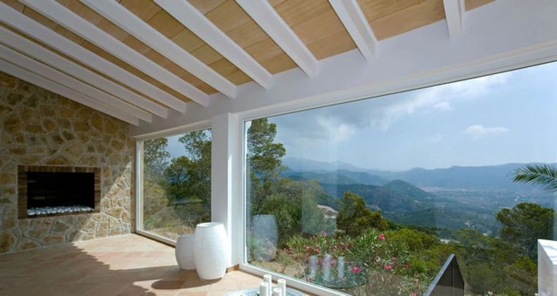 Modern living room with stone fireplace and floor-to-ceiling windows overlooking a mountain valley