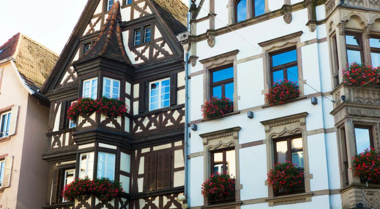 Half-timbered houses with flower boxes and blue-trimmed windows on a European street
