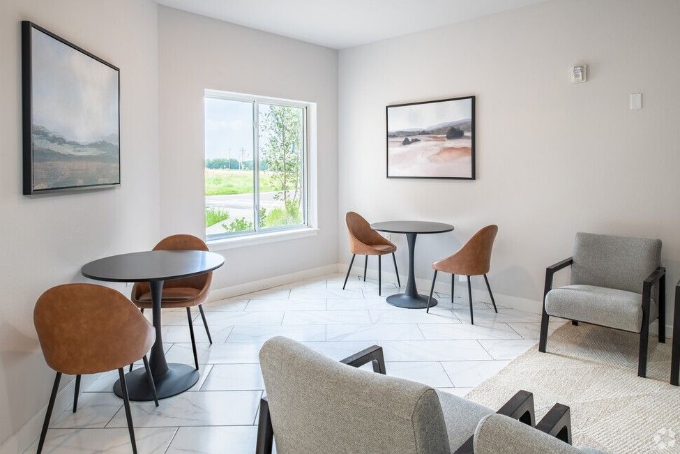 A living room with tables and chairs and a large window.