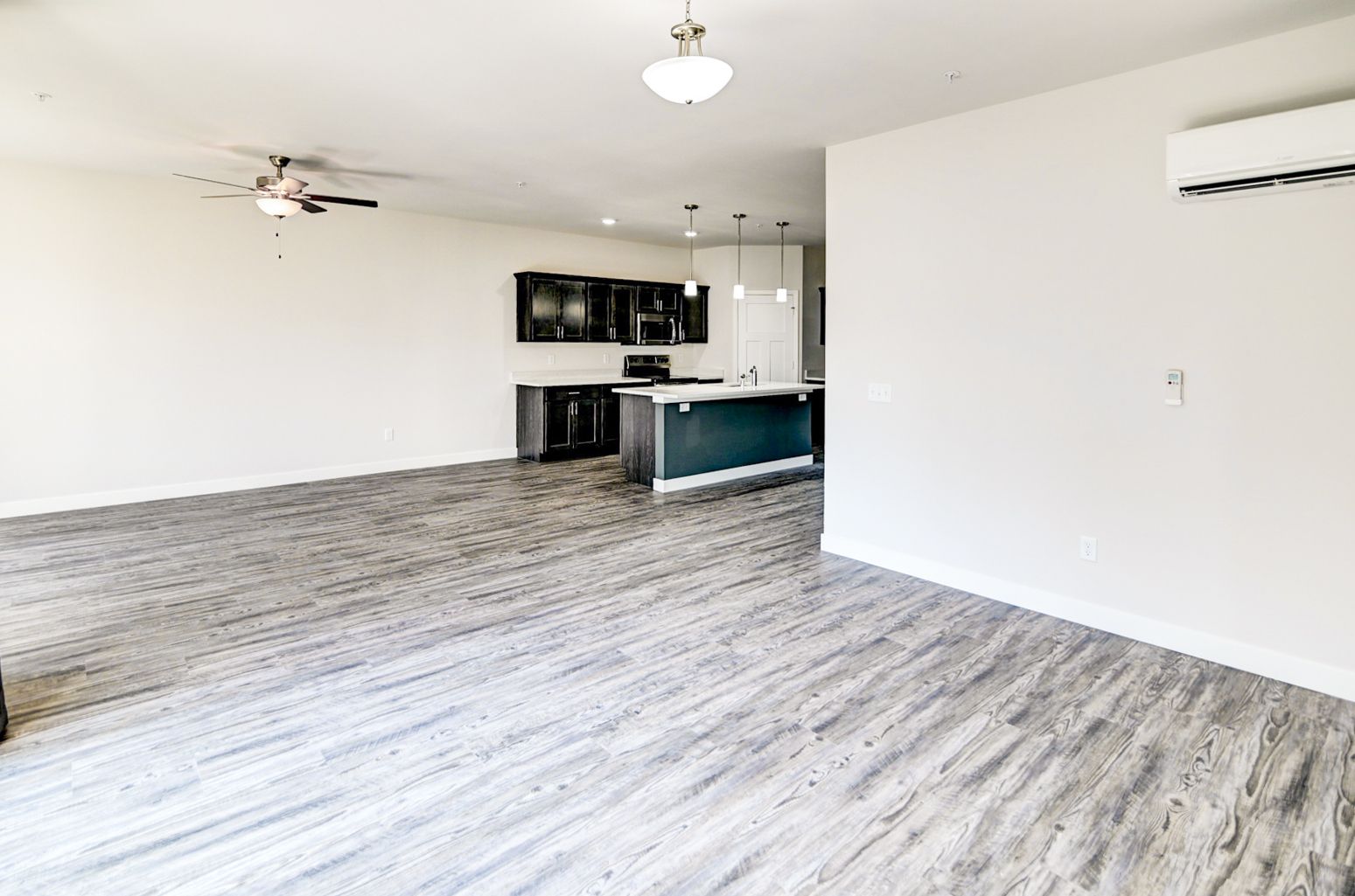 An empty living room with hardwood floors and a ceiling fan.