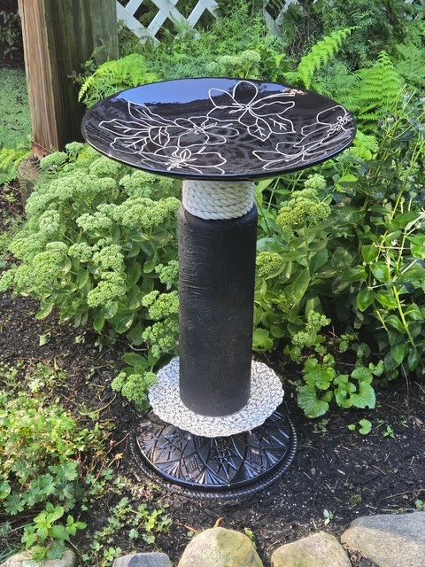 Black and white handmade bird bath with a patterned glass bowl