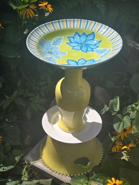Yellow and blue handmade bird bath in a garden
