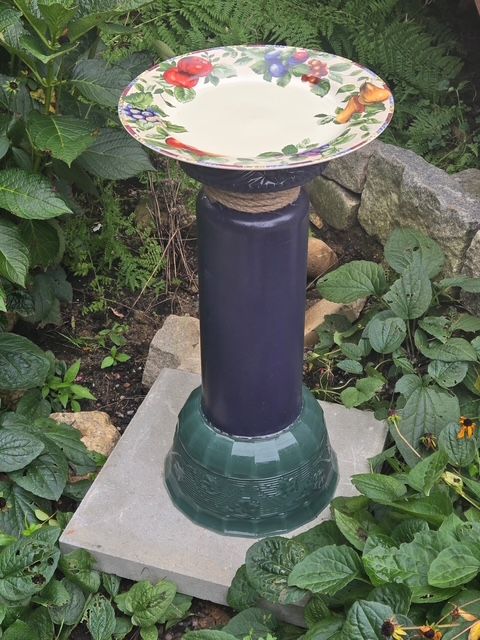 Floral handmade bird bath with a purple pedestal