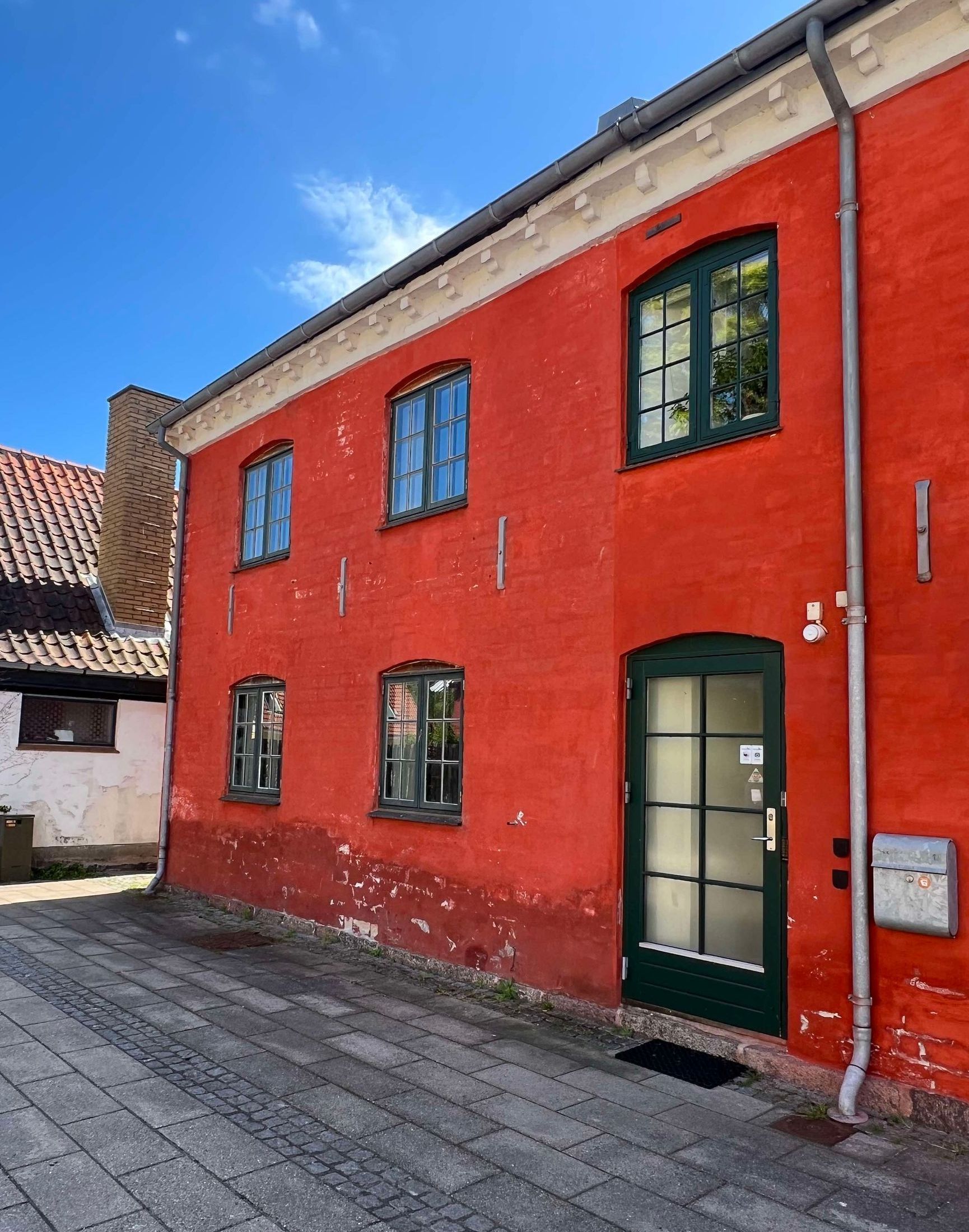 En rød bygning med en grøn dør og vinduer