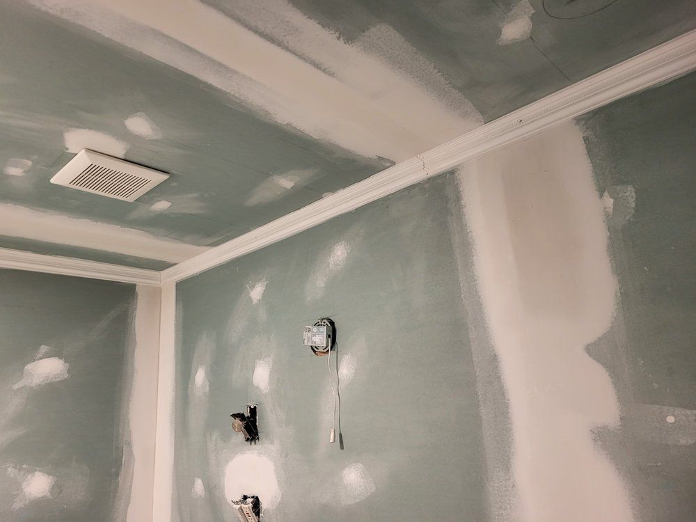 Partially finished room with taped drywall seams and patchy green-gray walls and ceiling