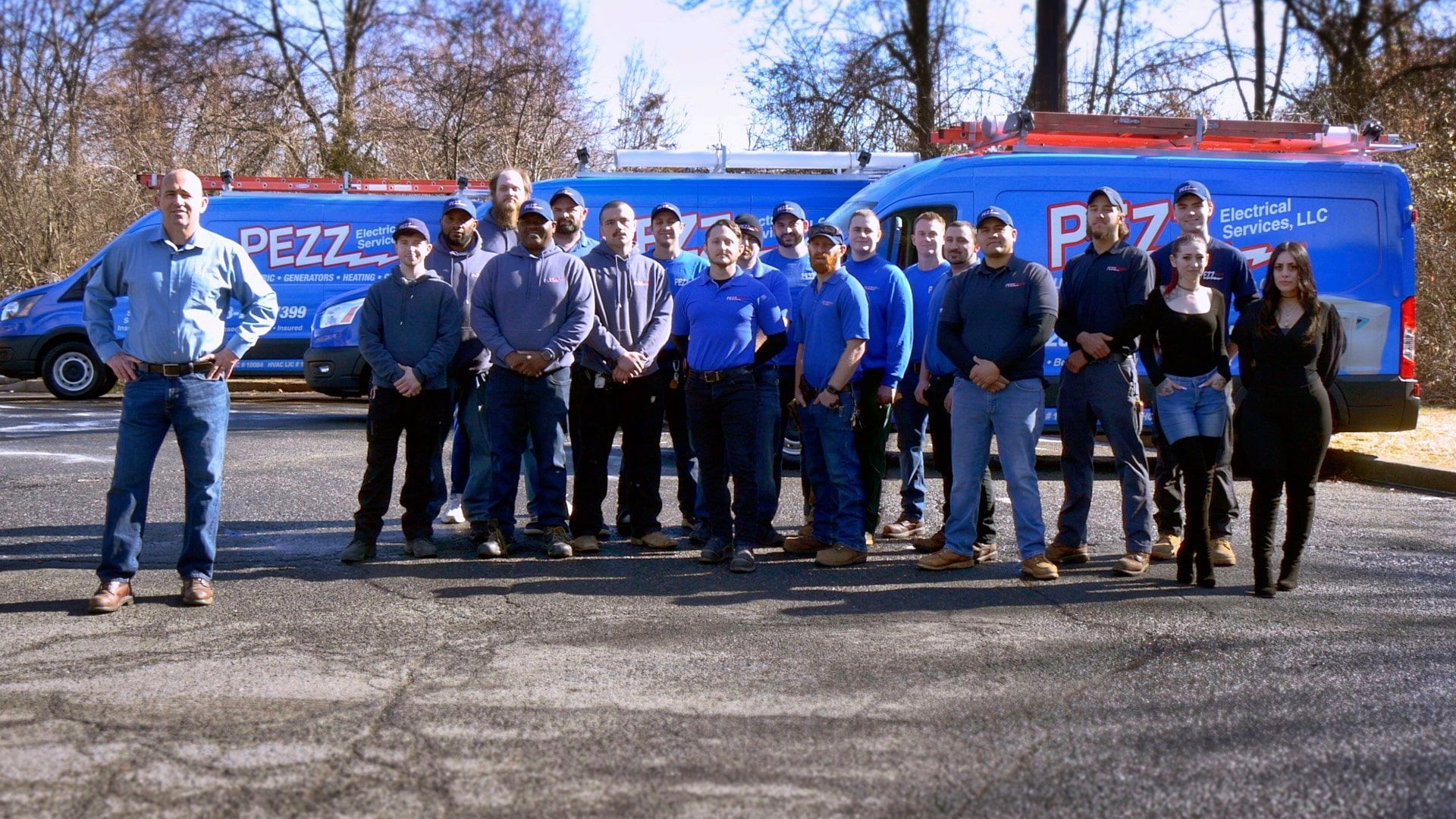Group of people posing in front of a blue delivery van on a sunny day