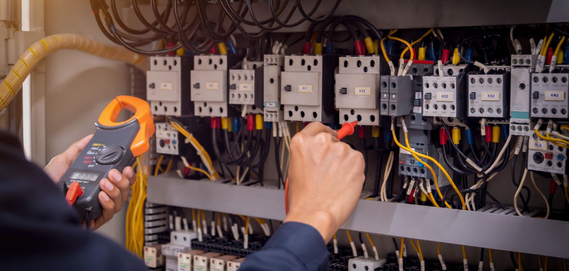 Technician testing electrical control panel wiring with a handheld meter
