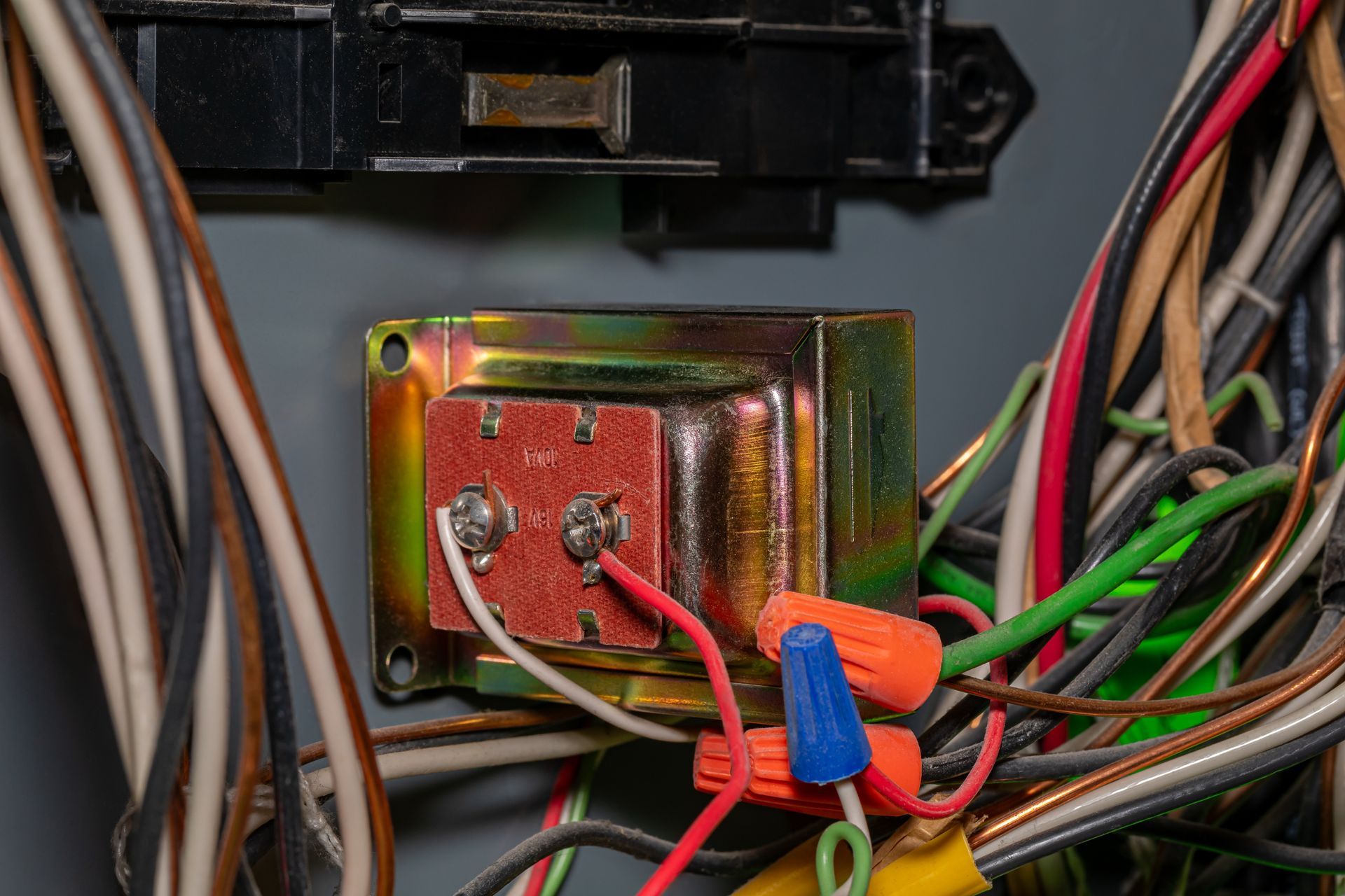Close-up of electrical wiring connected to a metal transformer inside a device cabinet