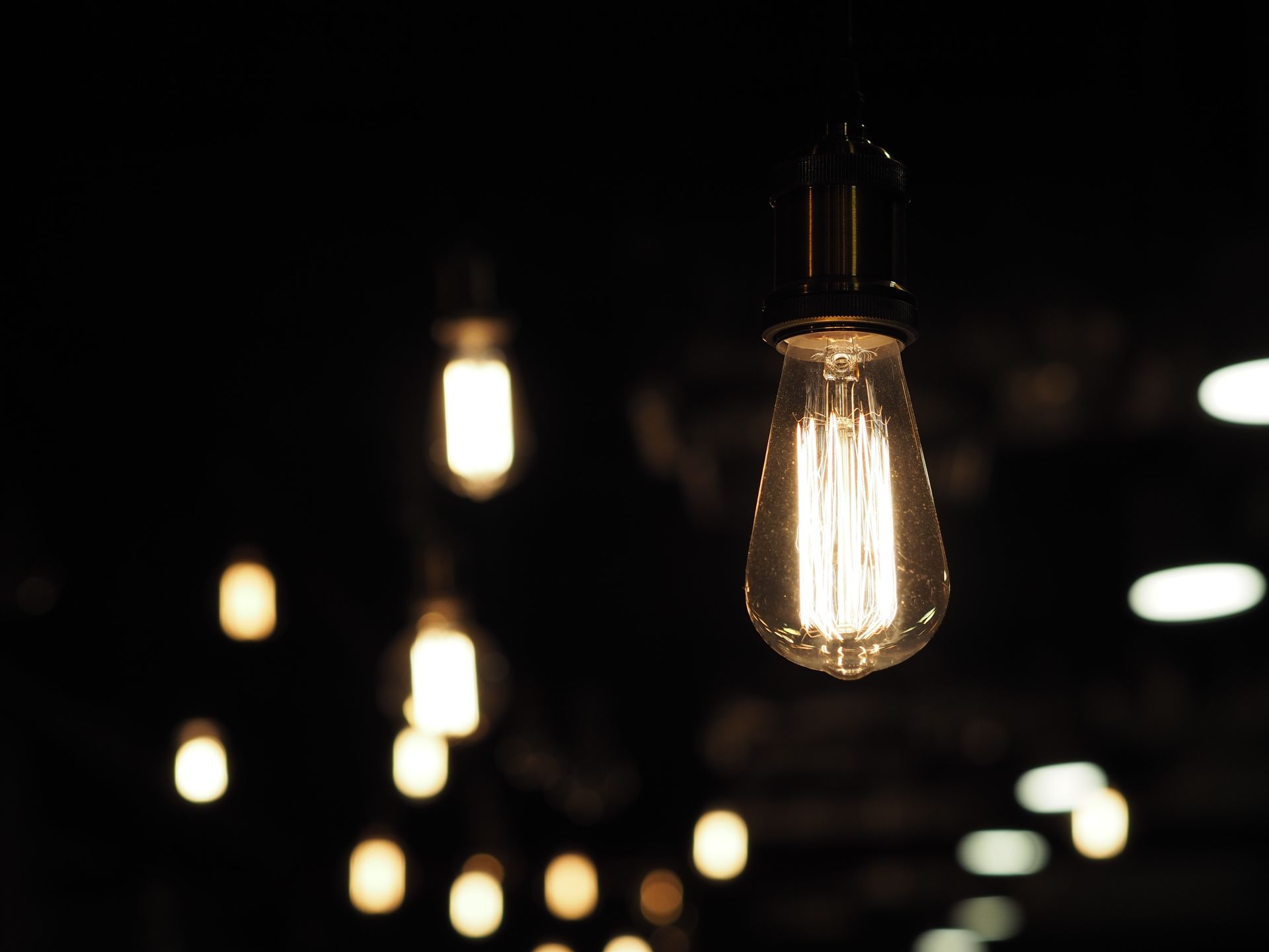 Glowing vintage light bulbs hanging in a dark, blurred interior