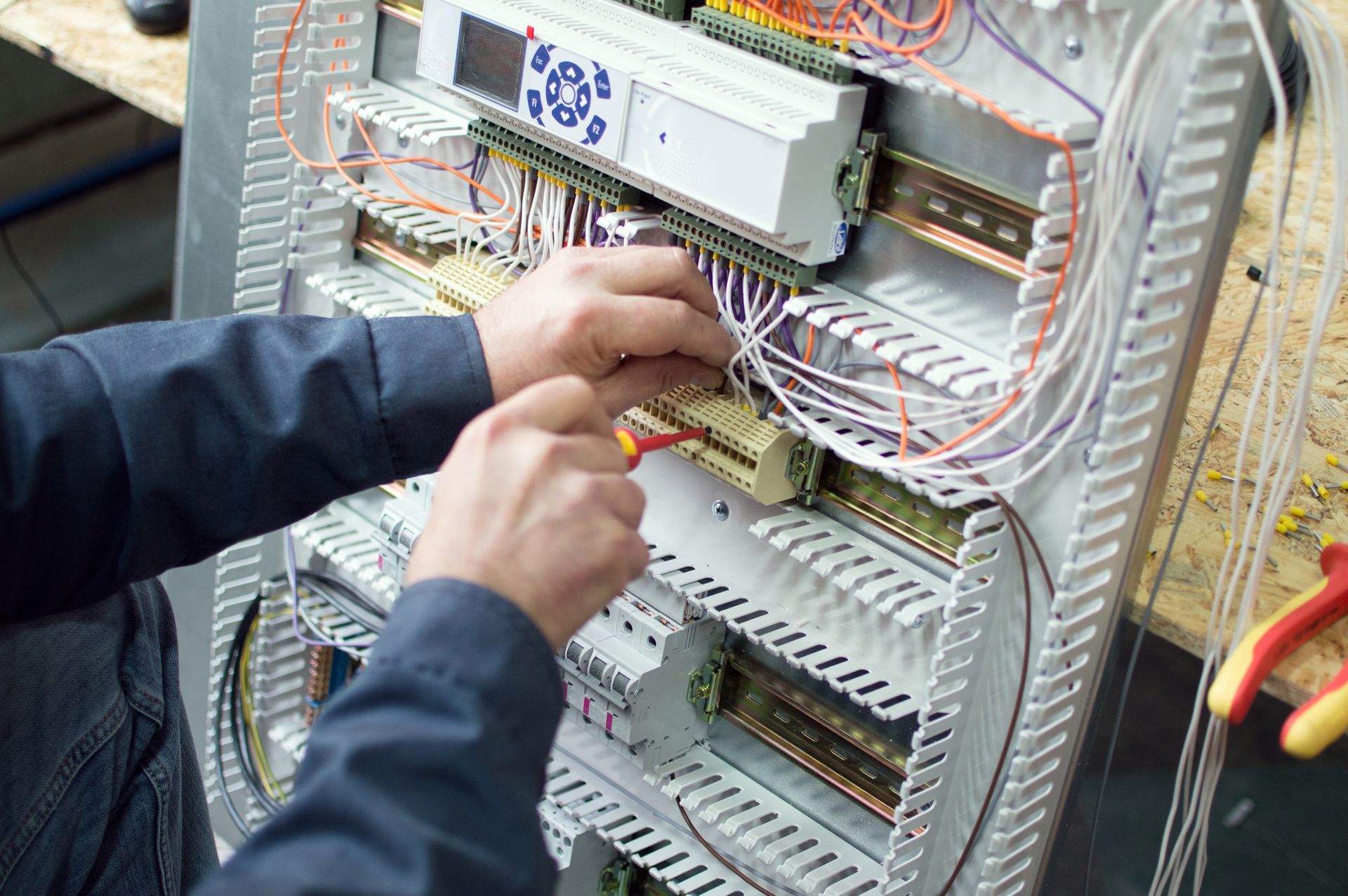 Technician wiring an electrical control panel with bundled cables and circuit modules