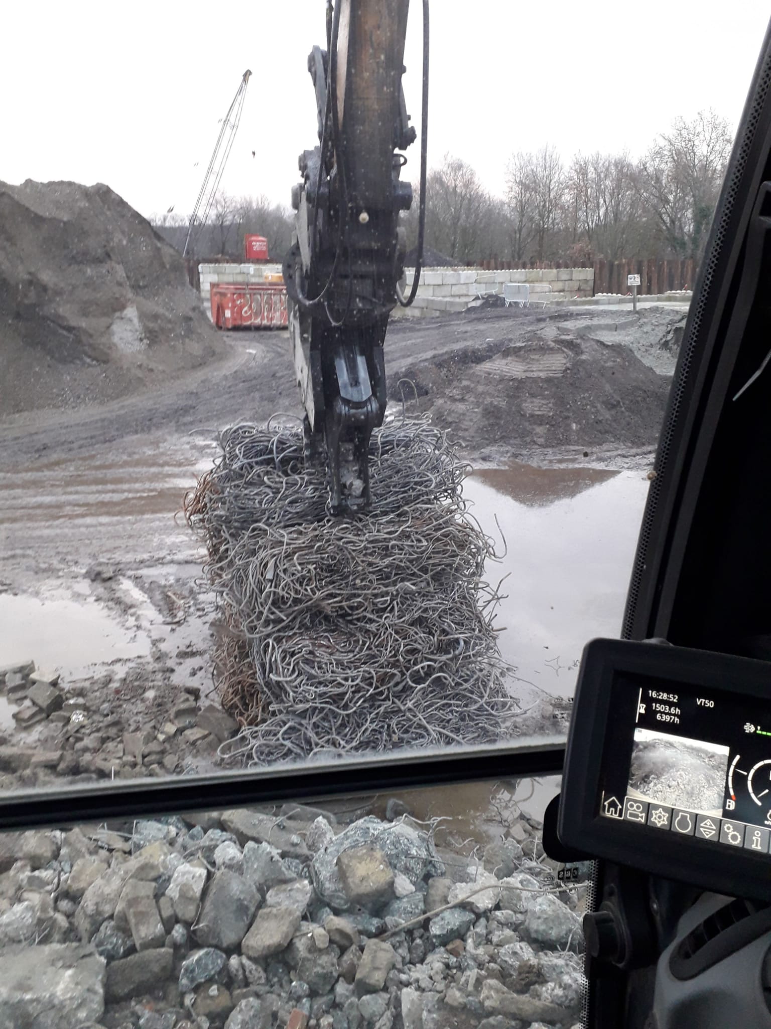 Graafmachine stort rotsen in een modderige steengroeve, gezien vanuit de cabine.
