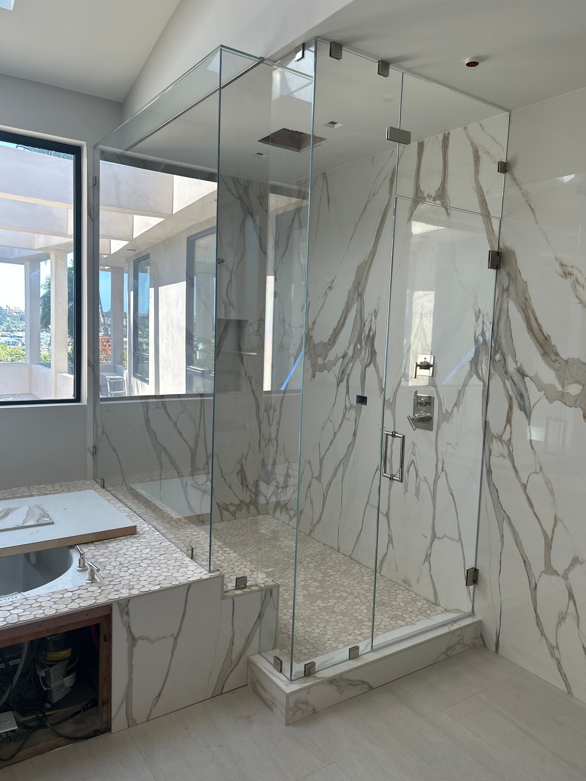 Modern bathroom with a glass shower enclosure and marble walls and floor.