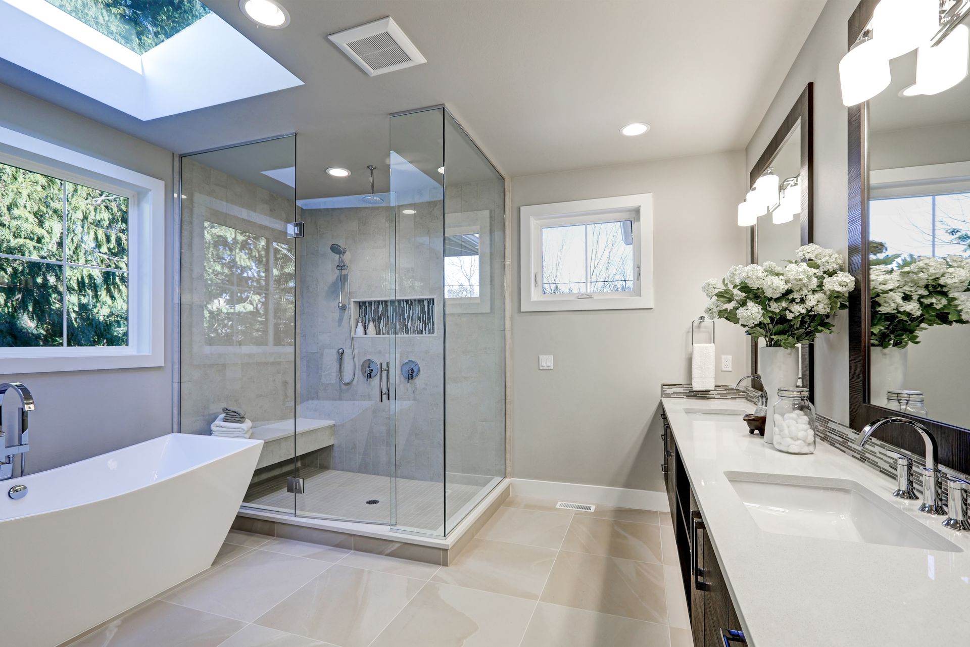 Modern bathroom with frameless glass shower enclosure, freestanding tub and dual vanity