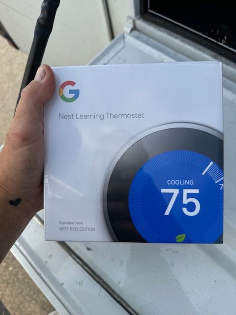 A person is holding a box of a google nest learning thermostat