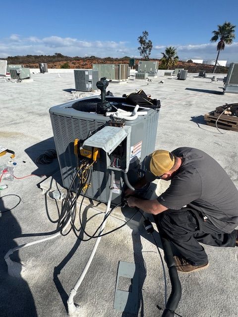 A man is working on an air conditioner on a roof