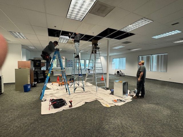 A group of people are working on a ceiling in a large room.