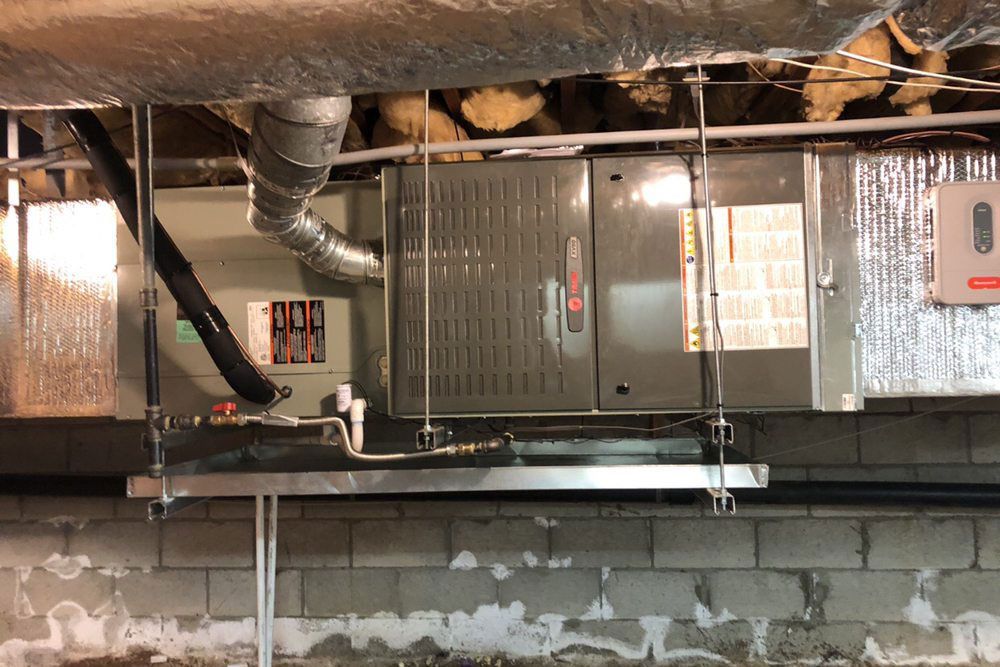 An air conditioner is hanging from the ceiling of a basement.
