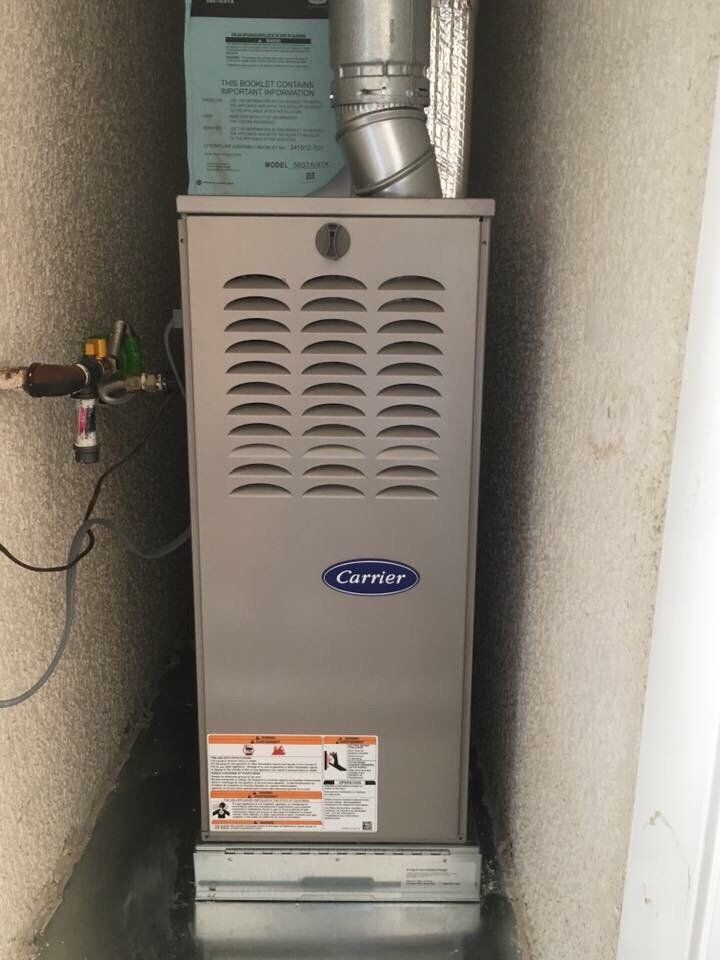 A carrier air conditioner is sitting in a corner of a room.
