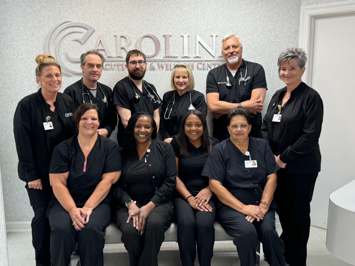 A group of people posing for a picture in front of a sign that says carolina acute care & wellness center