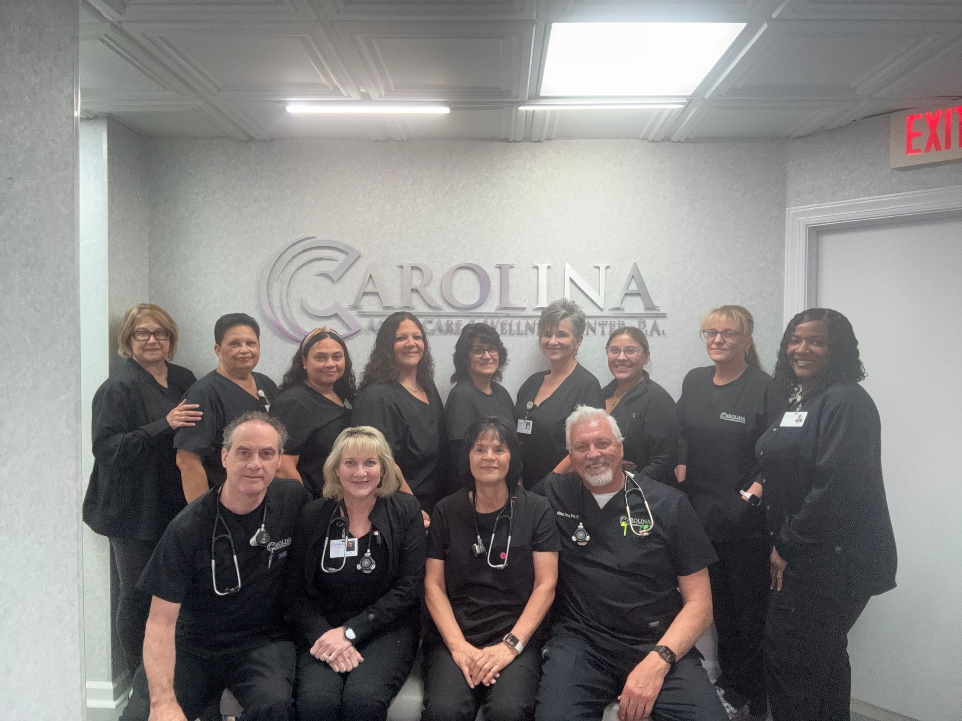 A group of people posing for a picture in front of a sign that says carolina acute care & wellness center
