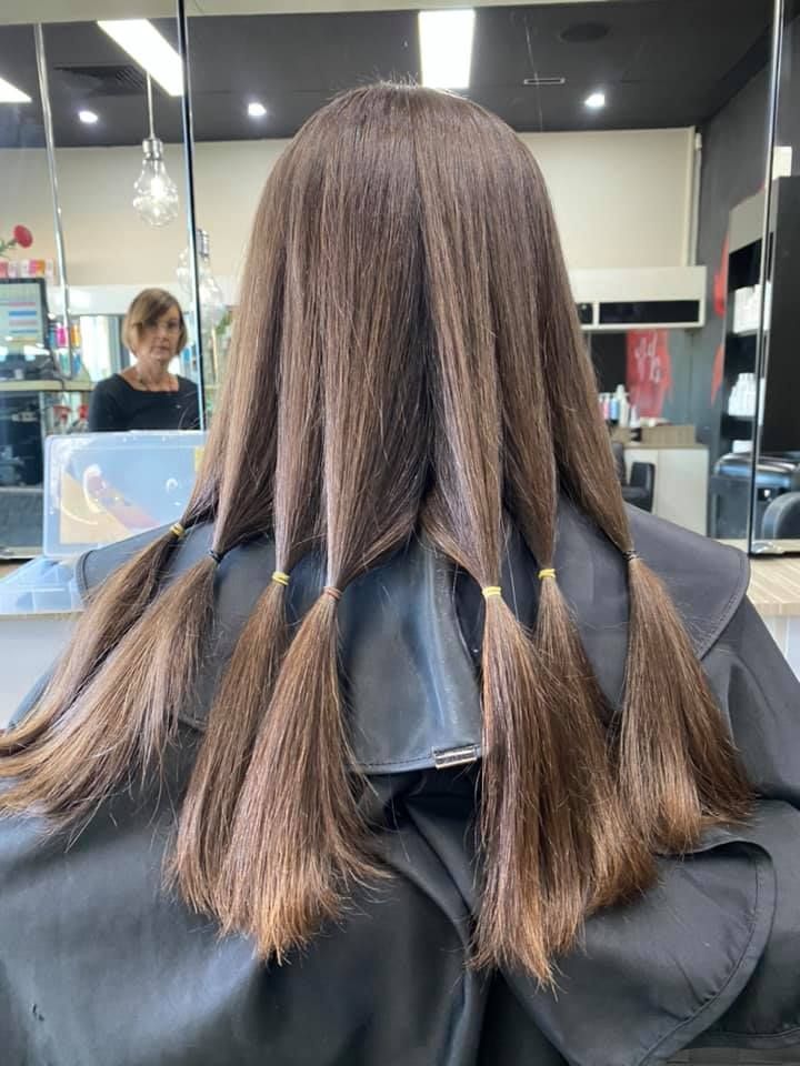 A Woman Is Getting Her Hair Cut in A Salon — Hair It Is In Balgownie, NSW