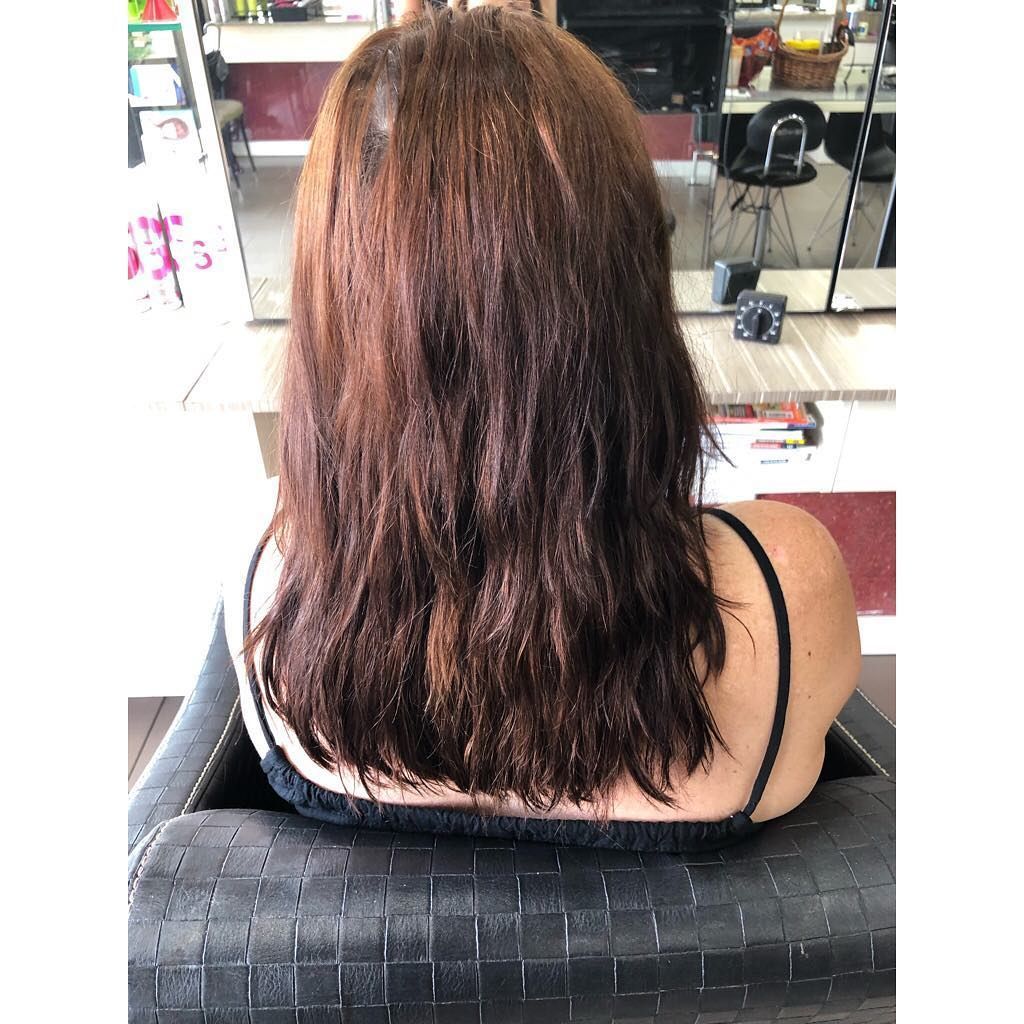 A Woman with Long Brown Hair Is Sitting in A Chair in A Salon — Hair It Is In Balgownie, NSW