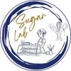 Logo Sugar Lab blu e bianco con un pasticcere, una vetrina e delle fruste in un disegno circolare.