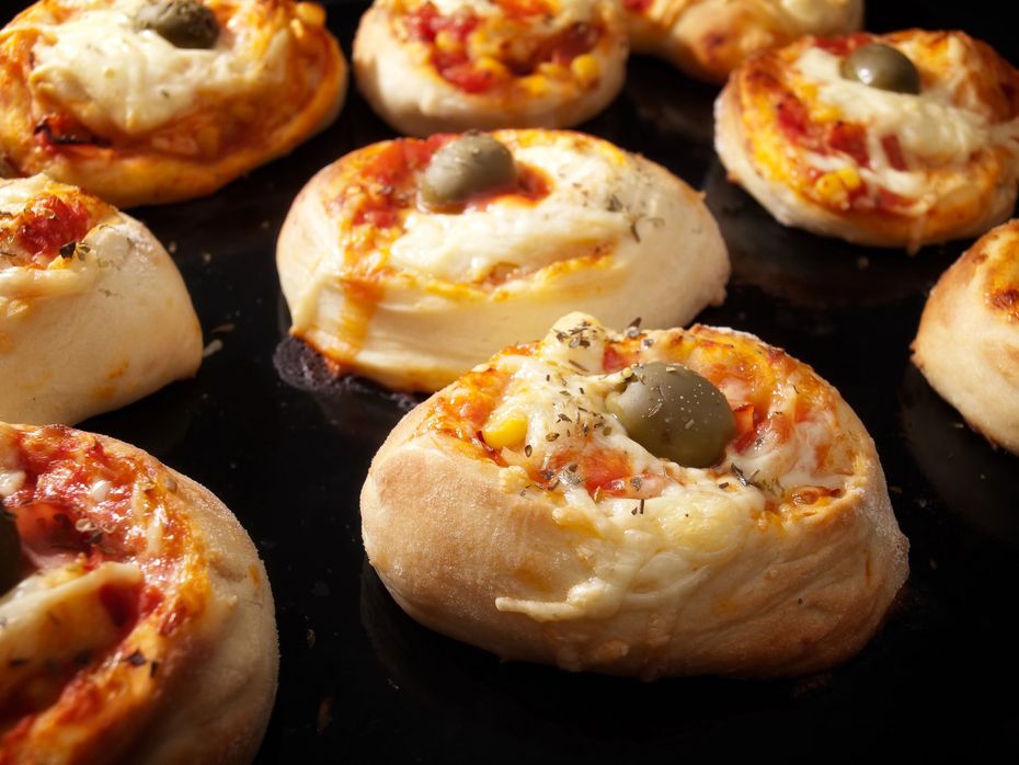 Vassoio di mini involtini di pizza conditi con salsa di pomodoro, formaggio e olive, in forno