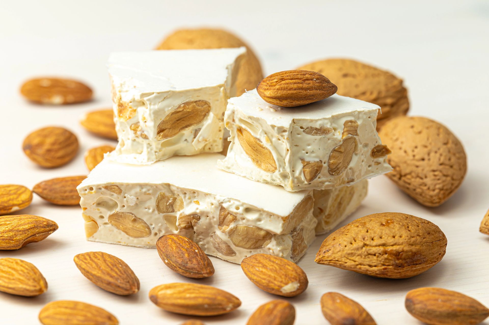 Cubetti di torrone bianco con mandorle sparse su uno sfondo chiaro